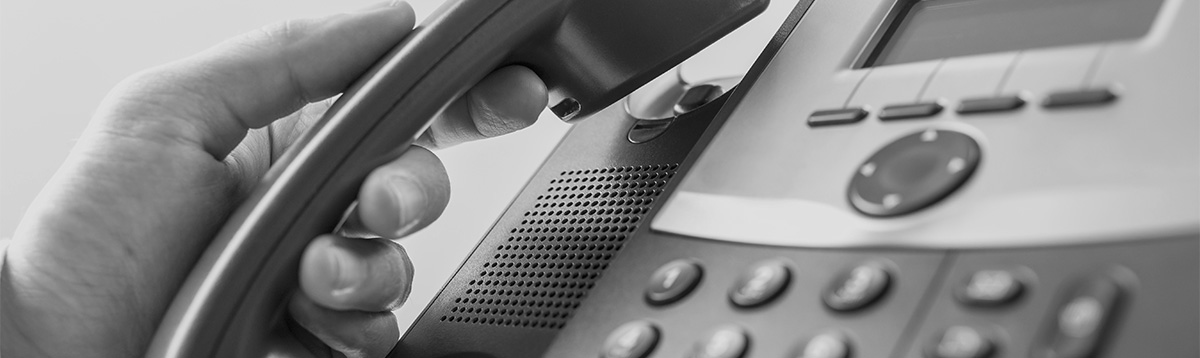 Closeup of male operator about to answer a phone call as he picks up a handset of a classical black landline telephone. Retro filter effect.